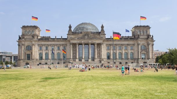 Reichstag in Berlin mit vielen Menschen auf der Wiese vor dem Gebäude.