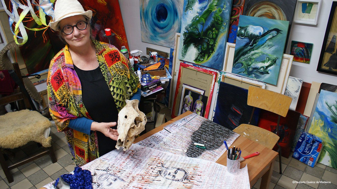 Hanna Mauermann steht in ihrem Atelier und zeigt ihre Kunst.
