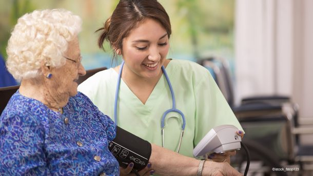 Junge Krankenschwester mißt den Blutdruck bei einer Seniorin.