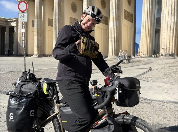 Christopher mit voll bepacktem Fahrrad vor dem Brandenburger Tor in Berlin beim Start seiner vierten Etappe von Berlin nach Marokko.
